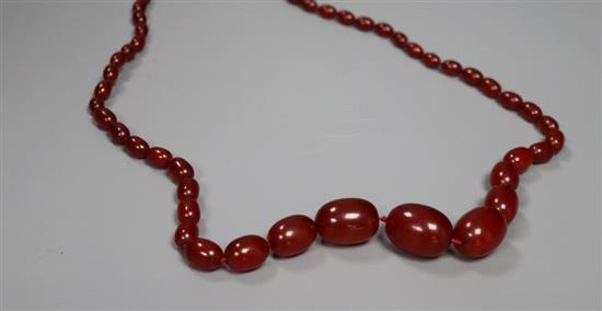 A single strand graduated oval simulated cherry amber necklace, 72cm, gross 64 grams.